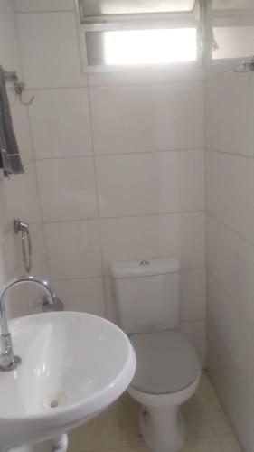 a white bathroom with a toilet and a sink at Suites Clarinda in Capitólio