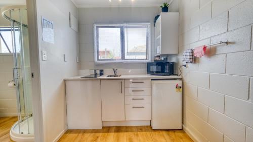 a small kitchen with a sink and a refrigerator at Wayfarer Motel in Kaitaia