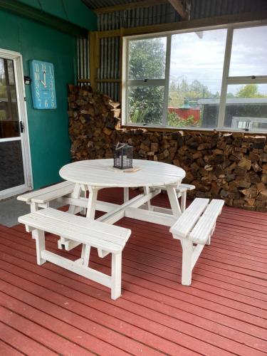 a picnic table and two benches on a porch at Waitomo Farmstay - Kiwi Cabin 5 in Waitomo Caves
