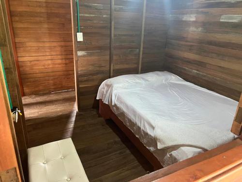 a small bed in a room with wooden walls at Posada el arrecife in Nuquí