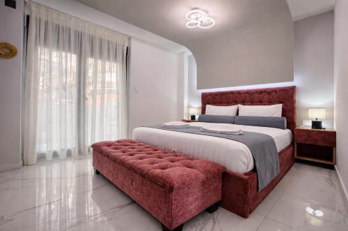 a bedroom with a large bed and a red bench at Candi Luxury Suites 2 in Neos Marmaras
