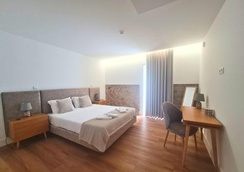a bedroom with a bed and a desk and a chair at Quinta das Aromáticas in Malta