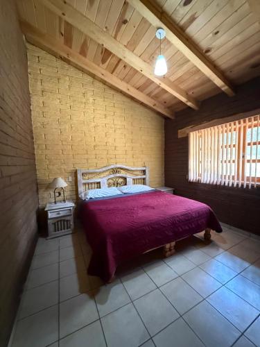 a bedroom with a bed with a red bedspread at Cabaña Cuevas Tapalpa in Tapalpa