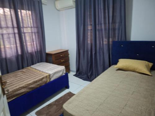 a bedroom with two beds and a window with curtains at Zara Appartement in Paramaribo