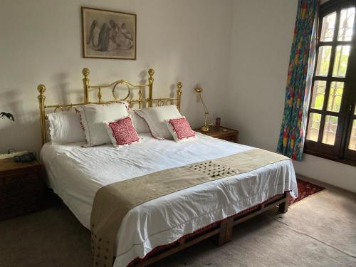 a bedroom with a bed with white sheets and red pillows at Hacienda Bugambilias Boutique Colonial in Cedro