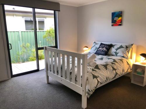 a white crib in a room with a window at Modern Spacious Manapouri Home in Manapouri