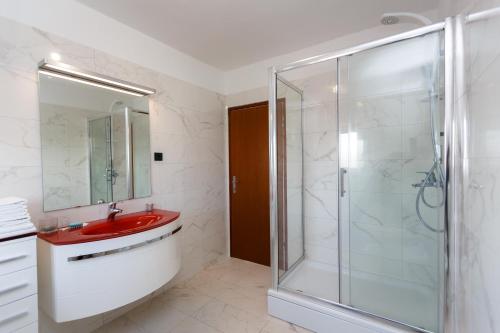 a bathroom with a red sink and a glass shower at Adria Holiday Home in Pinezici