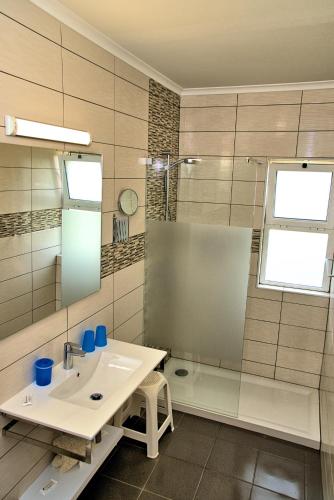 a bathroom with a sink and a shower and a mirror at Tonel Apartamentos Turisticos in Sagres