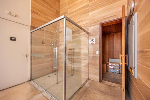 a glass shower in a bathroom with wooden walls at Apartamento Moderno Premium - Cittyplex in Osasco
