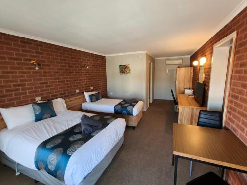 a hotel room with two beds and a brick wall at Barham Riverland Motel in Barham