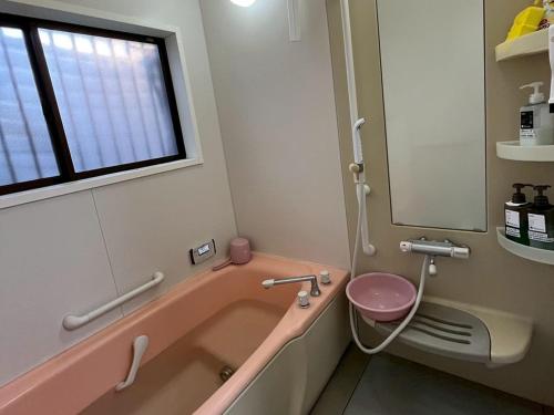 a bathroom with a pink tub and a pink toilet at 一棟貸の宿さくらんぼ in Kami-yuge