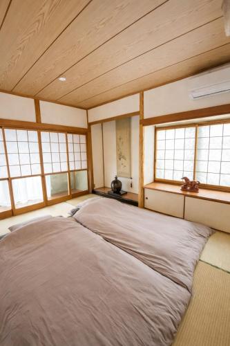 a bedroom with two beds in a room with windows at 一棟貸の宿さくらんぼ in Kami-yuge