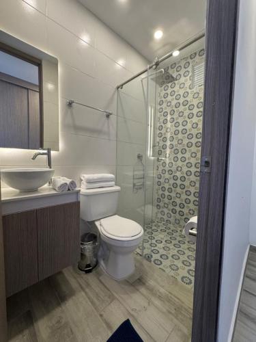 a bathroom with a toilet and a glass shower at Oasis Villeta Apartamento in Villeta