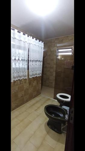 a bathroom with a black toilet and a shower at Casa Quarto 3 in Jaraguá do Sul