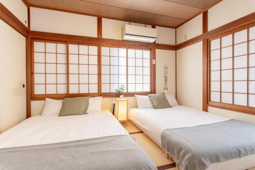 two beds in a room with windows at - 旅time 粉浜照 - 玉出駅まで徒歩3分 住吉大社まで徒歩13分 最大6人宿泊可能 in Osaka