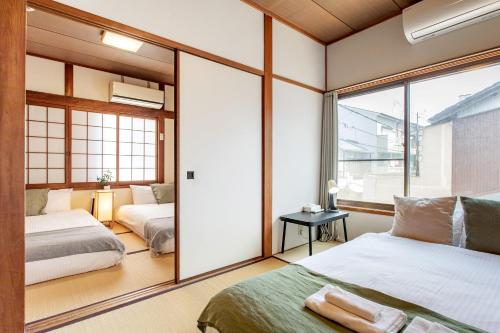 a bedroom with two beds and a large window at - 旅time 粉浜照 - 玉出駅まで徒歩3分 住吉大社まで徒歩13分 最大6人宿泊可能 in Osaka