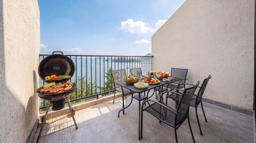 a balcony with a grill and a table with food at Yeosu Bokja Spa Pension in Yeosu