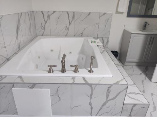 a bathroom with a white tub with two faucets at Knights Inn London Ontario in London