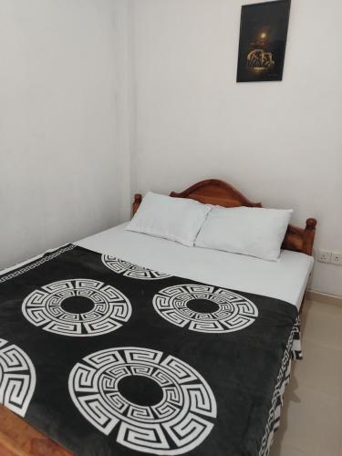 a bed with a black and white blanket on it at Phoenix Crest Cottage in Haputale