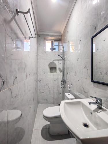 a white bathroom with a sink and a toilet at Al-mendhiry Apartment in Zanzibar City