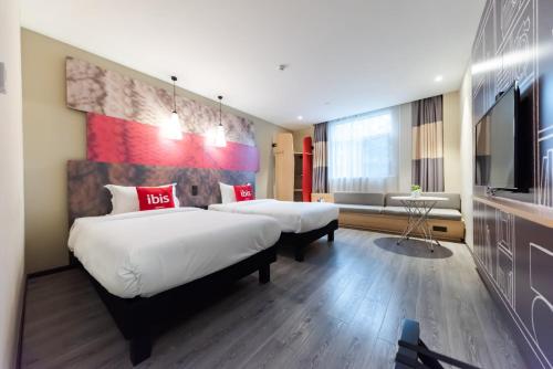 a hotel room with two beds and a flat screen tv at Ibis Yixing Longbeishan Forest Park in Yixing