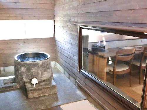 a room with a tub and a table and a chair at Auberge Ninguruforet in Biei