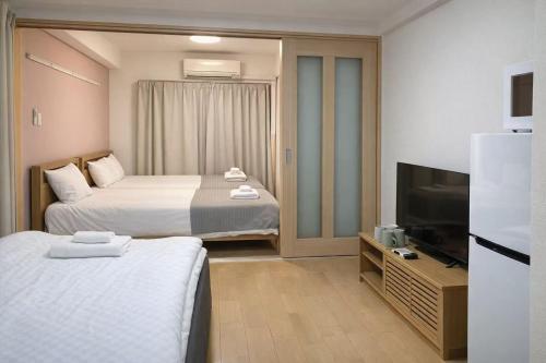 a hotel room with two beds and a flat screen tv at 桜の恋 in Osaka