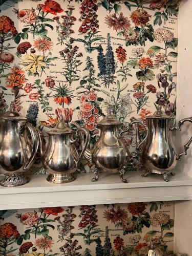 a shelf with four tea pots on a floral wallpaper at Aaron House of Niagara Falls in Niagara Falls