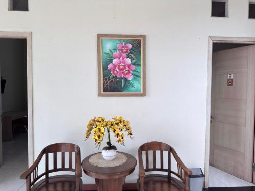 a table with two chairs and a vase with flowers at Guesthouse Anggrek BSD Syariah in Jombang-kulon