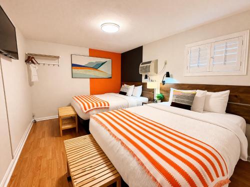 two beds in a hotel room with orange walls at The City Center Motel in Medford