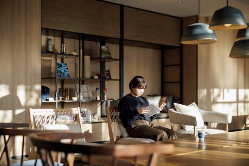 a woman sitting in a chair reading a book at Fairfield by Marriott Hiroshima Sera in Sera