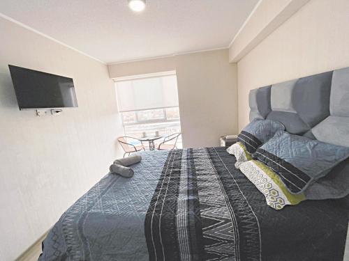 a bedroom with a bed and a tv on the wall at Apacible y acogedora habitación con vista a Barranco in Lima