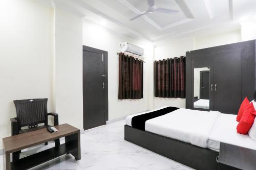a bedroom with a bed and a chair and a desk at Hotel O Figtree Premier in Patna