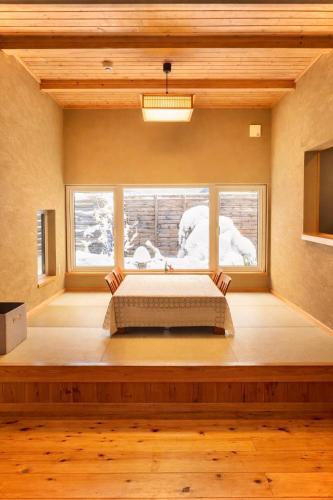 a bedroom with a bed and a large window at Auberge Ninguruforet in Biei