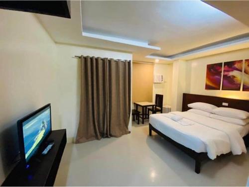 a bedroom with a bed and a flat screen tv at Tans Guesthouse in Boracay