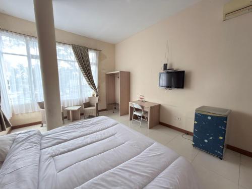 a bedroom with a large white bed and a television at Guesthouse Anggrek BSD Syariah in Jombang-kulon