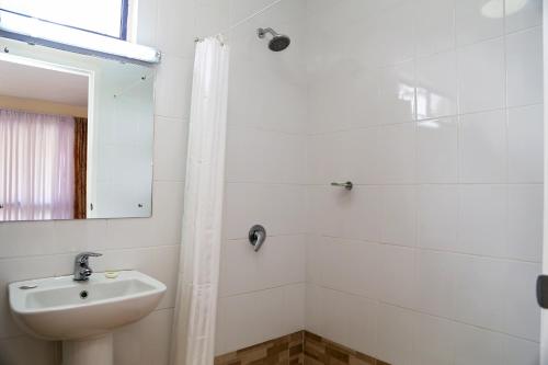 a white bathroom with a sink and a shower at Aquarius On The Beach in Nadi
