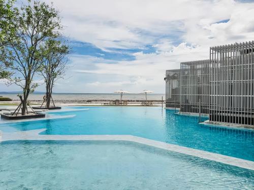 a swimming pool with blue water in front of the ocean at Veranda Residence Pattaya in Na Jomtien
