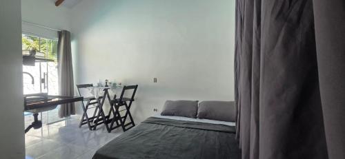 a bedroom with a bed and a dining room with a table at Arandu chalés maresias in São Sebastião