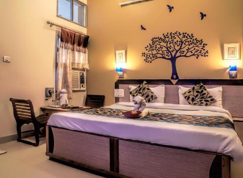 a bedroom with a bed with a tree on the wall at Hotel Laxmi Palace in Udaipur