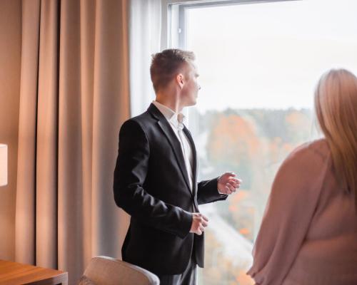 a man in a suit standing in front of a window at Courtyard Tampere City in Tampere