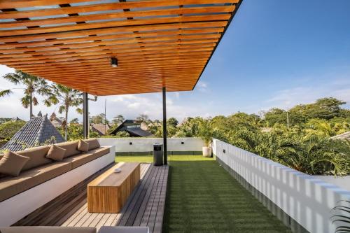 an outdoor patio with a bench and a wooden roof at Maui Bingin Villas in Uluwatu