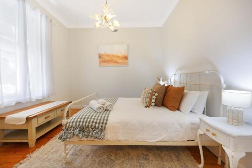 a bedroom with a bed and a table and a chandelier at Morrissey Cottage in Warrnambool
