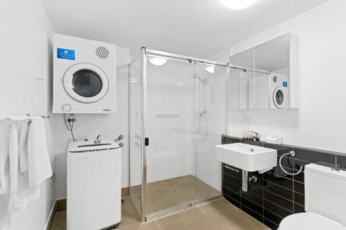 a bathroom with a shower and a sink and a washing machine at Direct Collective - Pavilion and Governor on Brookes in Brisbane