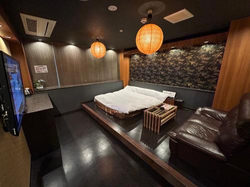 a bedroom with a bed and a couch and a tv at ホテル彩柏市若柴店 in Kashiwa
