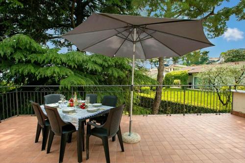 a table and chairs with an umbrella on a patio at Villa Alberti 900m from Garda lake with Garden in Salò