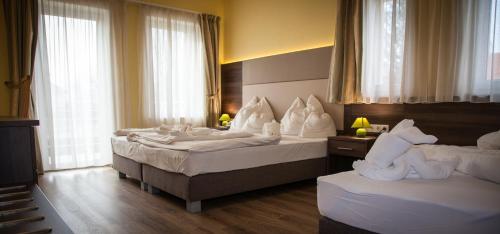 Habitación de hotel con 2 camas y almohadas blancas en Jade Hotel-Ezüsthíd Hotel, en Veszprém