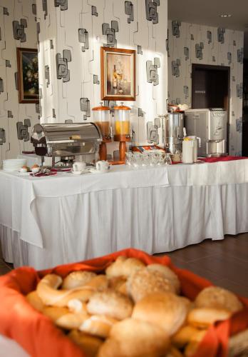 a table with a white table with a table with a tray of bread at Jade Hotel-Ezüsthíd Hotel in Veszprém