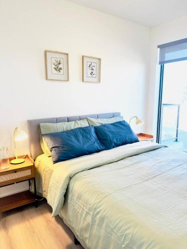 a bedroom with a large bed with blue pillows at Downtown Condo, Stylish Comfy in Calgary