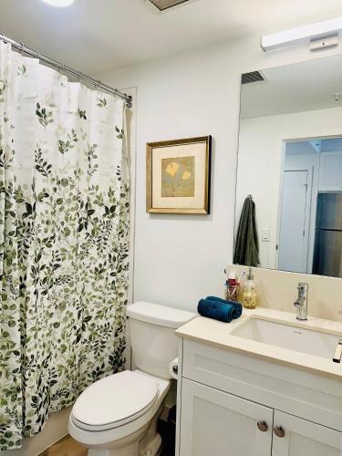 a bathroom with a toilet and a sink and a shower curtain at Downtown Condo, Stylish Comfy in Calgary